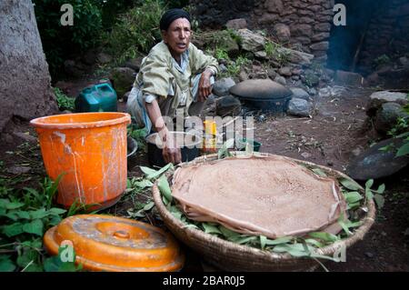 Femme cuisine Injera pancake comme du pain sur un mogogo au-dessus d'un feu. Lalibela, région d'Amhara, Ethiopie. Banque D'Images