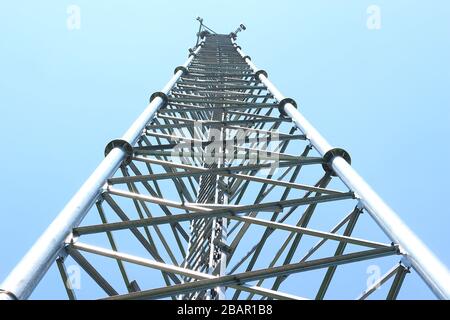 Cette photographie au niveau du sol représente la structure en acier complexe d'une tour de télécommunication, mettant en valeur sa construction robuste. Banque D'Images