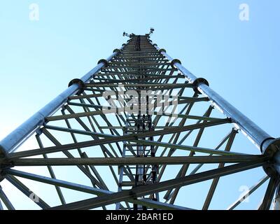 Cette photographie au niveau du sol représente la structure en acier complexe d'une tour de télécommunication, mettant en valeur sa construction robuste. Banque D'Images