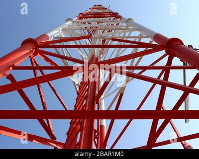 Cette photographie au niveau du sol représente la structure en acier complexe d'une tour de télécommunication, mettant en valeur sa construction robuste. Banque D'Images