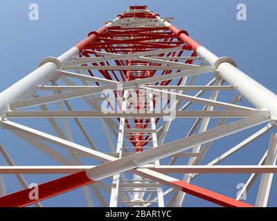 Cette photographie au niveau du sol représente la structure en acier complexe d'une tour de télécommunication, mettant en valeur sa construction robuste. Banque D'Images