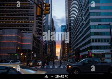 Philadelphie, PA/USA-fév 29, 2020: Un coucher de soleil brille au-dessus d'une intersection animée des rues Market et 15ème, en regardant à l'ouest de l'hôtel de ville. Banque D'Images