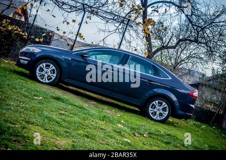 Magnifique berline Ford Mondeo MK 4 avec beaucoup d'équipement supplémentaire. Séance photo dans un parking près d'une forêt brune d'automne. Couleur grise avec chrome Banque D'Images