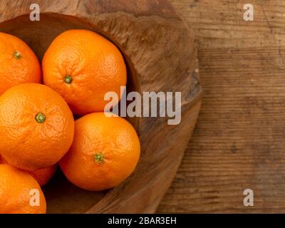 fruits orange mandarins frais dans un bol en bois sur une planche en bois vue sur le dessus espace copie Banque D'Images