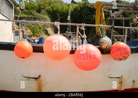 Bouées rouges vives sur un bateau de pêche traditionnel sur la plage du petit village de pêcheurs de Cadgwith, Cornwall, Angleterre, Royaume-Uni. Banque D'Images