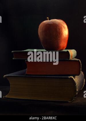 Apple et des livres dans le style Chiaroscuro qui est l'effet de la modélisation de la lumière dans la photographie Banque D'Images