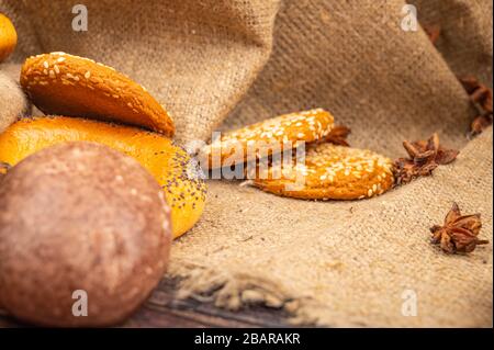 Pain d'épice au chocolat, petits pains, biscuits et anis étoilé sur fond de tissu grossier. Gros plan Banque D'Images