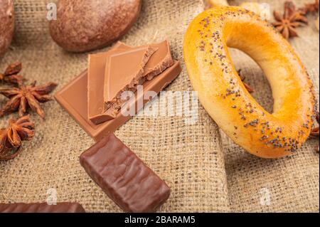 Pain d'épice au chocolat, bagels, chocolat et anis étoilé sur fond de tissu grossier. Gros plan Banque D'Images