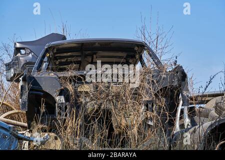 vieux cadre gris voiture démontée voiture avec des pièces rouillées dans la rue près de la clôture. Banque D'Images