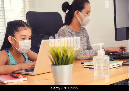 maman travaillant à la maison portant un masque de protection avec son enfant sur la table tout en écrivant un rapport. femme travaillant à la maison, pendant en quarantaine isolati Banque D'Images