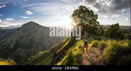 Fille debout sur le sommet du pic de Little Adam au coucher du soleil à Ella, Sri Lanka Banque D'Images