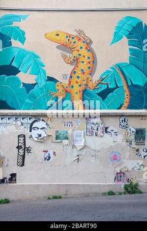 Une représentation jaune vif colorée d'un grand lézard grimpant sur un mur. L'art de rue par l'artiste graffiti connu sous le nom de Louyz. Butte aux Cailles, Paris. Banque D'Images