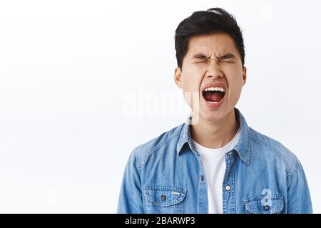 Portrait de jeune homme d'asie soyeuse qui pleut comme bébé, pleurant et criant se plaindre de la vie cruelle injuste, des yeux étroits et criant ennuyé, debout Banque D'Images