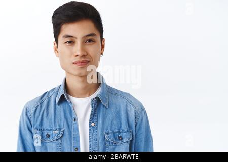 Gros plan portrait de beau hipster asiatique élégant, homme avec oreille souriant appareil photo heureux, l'air enthousiaste et sain, travail de recherche d'étudiant Banque D'Images