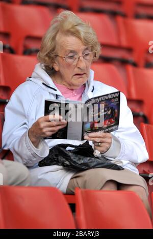 Un fan de Charlton Athletic lit le programme d'allumettes dans les tribunes avant le jeu Banque D'Images