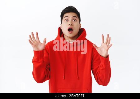 Un portrait à la taille d'un homme asiatique choqué et surpris lève les mains pour attraper quelque chose qui tombe du ciel, haletant et avoir l'air alarmé ou focalisé, voir l'objet Banque D'Images