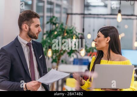 Le responsable explique à son employé comment terminer ses tâches. Collègues discutant d'un projet en se tenant dans un bureau. Banque D'Images