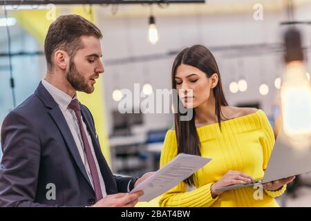 Le responsable explique à son employé comment terminer ses tâches. Collègues discutant d'un projet en se tenant dans un bureau. Banque D'Images