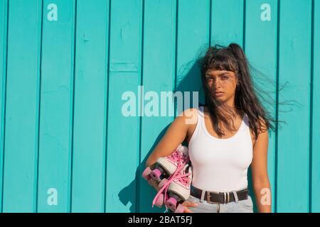 La jeune dame qui tient son rouleau patine dans ses bras Banque D'Images