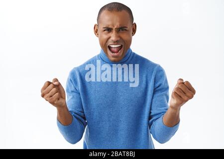 Portrait d'un homme américain africain fort et enthousiaste, hurlant la confiance, regardant la télévision en ligne en direct du jeu de sport, chantant Banque D'Images