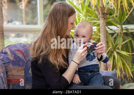 Maman met sur un masque de protection réutilisable fait maison à son petit fils. Banque D'Images