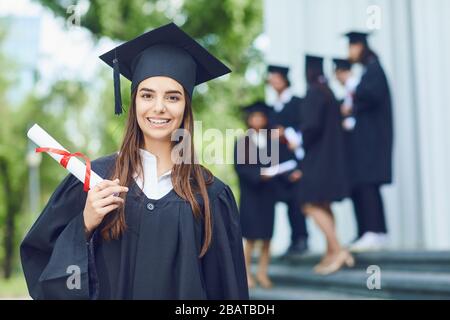 Une jeune femme diplômée dans le contexte des diplômés universitaires. Banque D'Images