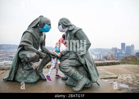 Pittsburgh, PA, États-Unis. 28 mars 2020. NOUVEAU en réponse au virus COVID-19 une personne intelligente a mis des masques sur le leader Seneca Guyasuta, à gauche et George Washington. La statue est appelée « points de vue ». Il donne sur la ville de Pittsburgh, PA. La ville est dans une commande de gouverneur Wolf « Stay at Home » depuis le 23 mars 2020. La statue marque l'extrémité la plus à l'ouest de He Grand View Scenic Byway, un officiel Pennsylvania Scenic Byway.UN père et une fille prennent une visite rapide du parc après avoir déposé de la nourriture à un parent. Crédit : Annie O'Neill/ZUMA Wire/Alay Live News Banque D'Images