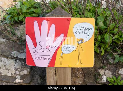 Un panneau dessiné à la main à l'extérieur d'une école conseillant en anglais et en gallois de ralentir avec les enfants traversant. Newport, Pembrokeshire. Pays de Galles. ROYAUME-UNI Banque D'Images