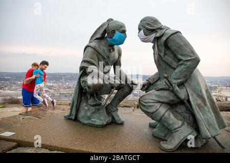 Pittsburgh, PA, États-Unis. 28 mars 2020. NOUVEAU en réponse au virus COVID-19 une personne intelligente a mis des masques sur le leader Seneca Guyasuta, à gauche et George Washington. La statue est appelée « points de vue ». Il donne sur la ville de Pittsburgh, PA. La ville est dans une commande de gouverneur Wolf « Stay at Home » depuis le 23 mars 2020. La statue marque l'extrémité la plus à l'ouest de He Grand View Scenic Byway, un officiel Pennsylvania Scenic Byway.UN père et une fille prennent une visite rapide du parc après avoir déposé de la nourriture à un parent. Crédit : Annie O'Neill/ZUMA Wire/Alay Live News Banque D'Images