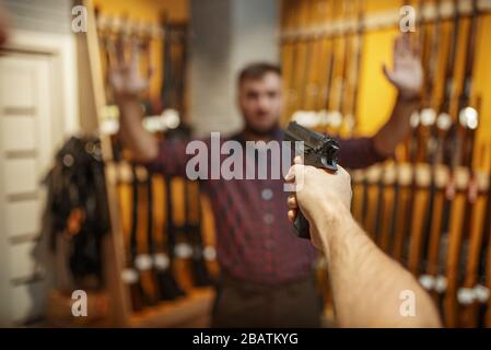 L'homme vise avec un nouveau pistolet sur le vendeur dans le magasin d'armes à feu Banque D'Images