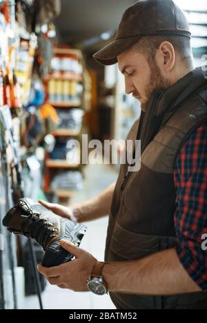 Homme choisissant des bottes pour les chasseurs dans la boutique des armes à feu Banque D'Images