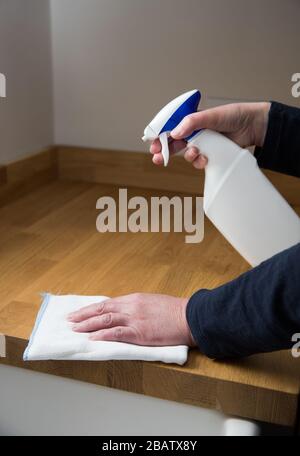 Un gros plan d'une paire de mains humaines nettoyant l'intérieur d'une cuisine avec un spray antibactérien pour désinfecter les surfaces de travail pendant le Coronavirus Banque D'Images
