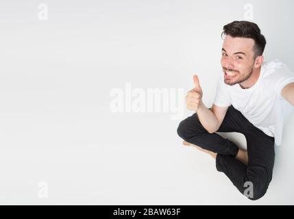 Jeune homme isolé en arrière-plan. Guy montre grand pouce vers le haut. Vue latérale de l'homme expressif joyeux et joyeux prendre la photo seul. Drôle et bizarre. Banque D'Images