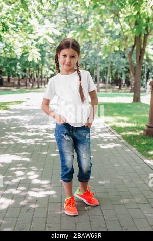 petite fille souriante modèle en chemise blanche posant dans le parc Banque D'Images