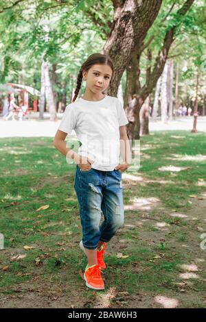 petite fille souriante modèle en chemise blanche posant dans le parc Banque D'Images