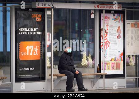 Varsovie, Pologne. 29 mars 2020. Un homme âgé portant un masque chirurgical est vu attendre à un arrêt de tramway dans le centre de Varsovie, en Pologne, le 29 mars 2020. Le 24 mars, le gouvernement polonais a annoncé de nouvelles restrictions à la circulation personnelle après avoir déjà fermé des écoles, des bars et des restaurants en plus de fermer les frontières aux étrangers. Les rassemblements de plus de deux personnes sont interdits en public jusqu'au 11 avril. Malgré des mesures plus strictes, le parti au pouvoir pour la loi et la justice a modifié les règles électorales de manière à ce que les élections présidentielles du 10 mai restent en place. Crédit: SIPA USA/Alay Live News Banque D'Images