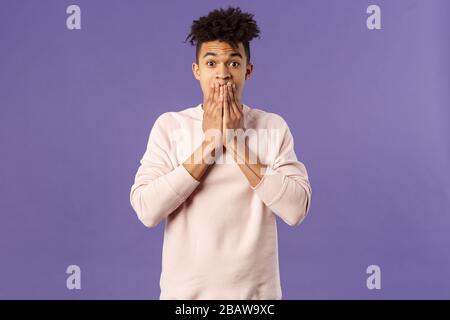 Portrait de jeune gars hispaniques choqués et impressionnés étant stupéfait par les nouvelles récentes à la télévision, tenir les mains sur la bouche, soulever les sourcils ne croient pas son Banque D'Images