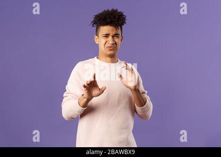 Phew l'éloigner de moi. Portrait de jeune homme déguisé qui a frappé quelque chose d'horrible, s'éloigner et le bloquer avec les bras levés, refuser de grimaquer avec Banque D'Images