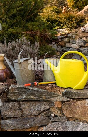 Arrosoirs. Arrosage du jardin. Outils du jardinier. Arrosoirs métalliques anciens se tenant sur une roche dans un jardin. Banque D'Images