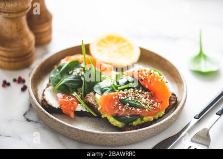 Toasts au saumon, purée d'avocat et de jeunes épinards. Apéritif, petit déjeuner, déjeuner ou en-cas sains Banque D'Images