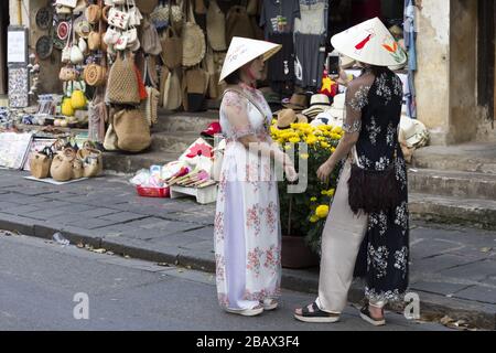 Deux filles vietnamiennes vêtues de vêtements ethniques traditionnels et portant des chapeaux de cône debout sur Hoi an Street pendant la célébration du nouvel an chinois asiatique Banque D'Images