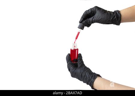 Flacon en verre avec liquide rouge, pipette avec sang et mains dans des gants de protection noirs Banque D'Images