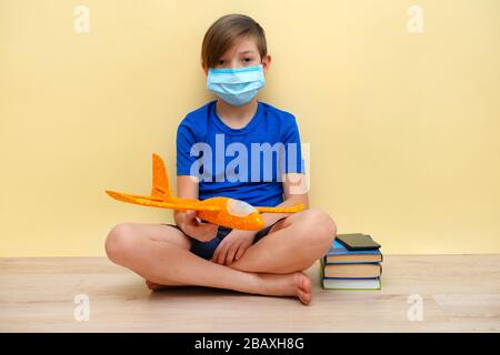 Un garçon de 9 ans dans un masque joue à la maison pendant la quarantaine et l'auto-isolation. Coronovirus 2019. Banque D'Images