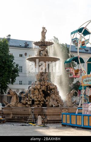 Tôt le matin à la fontaine baroque sur la place Residenz de Salzbourg, une roue Ferris pour enfants en arrière-plan, Autriche/Europe Banque D'Images