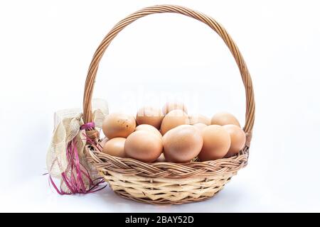 Œufs biologiques de ferme dans un panier en osier isolé sur fond blanc. Poulets œufs des zones écologiquement propres Banque D'Images