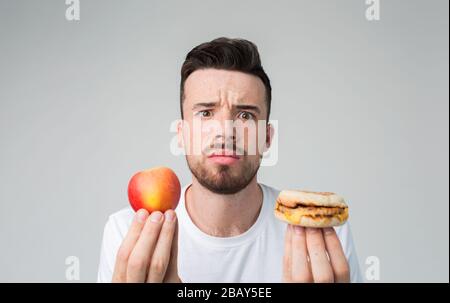 L'homme fait le choix entre la nourriture rapide et saine. Savoureux et utile le dilemme choisir un style de vie différent Banque D'Images