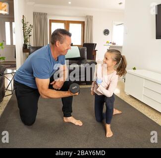 Arrêt COVID-19. Père et fille en quarantaine s'exerçant avec des haltères. Avantages de l'activité physique pendant le verrouillage. Rester à la maison, Banque D'Images