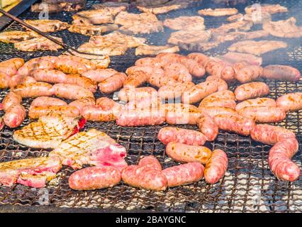 saucisses et steaks de porc cuits sur une grande baque avec des coals chauds et des herbes aromatiques Banque D'Images