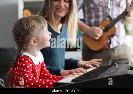 Les parents enseignent à la fille de jouer des instruments de musique Banque D'Images