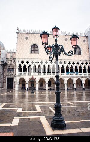 Lanterne de la vieille rue à Venise sur la place San Marco. Tôt le matin à la pluie. Ciel nuageux. Palais des Doges (Palazzo Ducale) et porte de Carta sur le fond. Banque D'Images